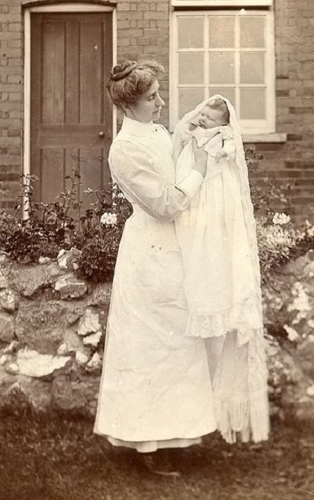 Edwardian nurse poses with a new baby.
