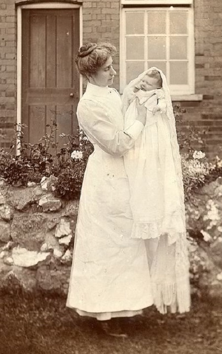 Edwardian nurse poses with a new baby.