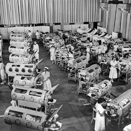 Nurses assisting patients with iron lungs.